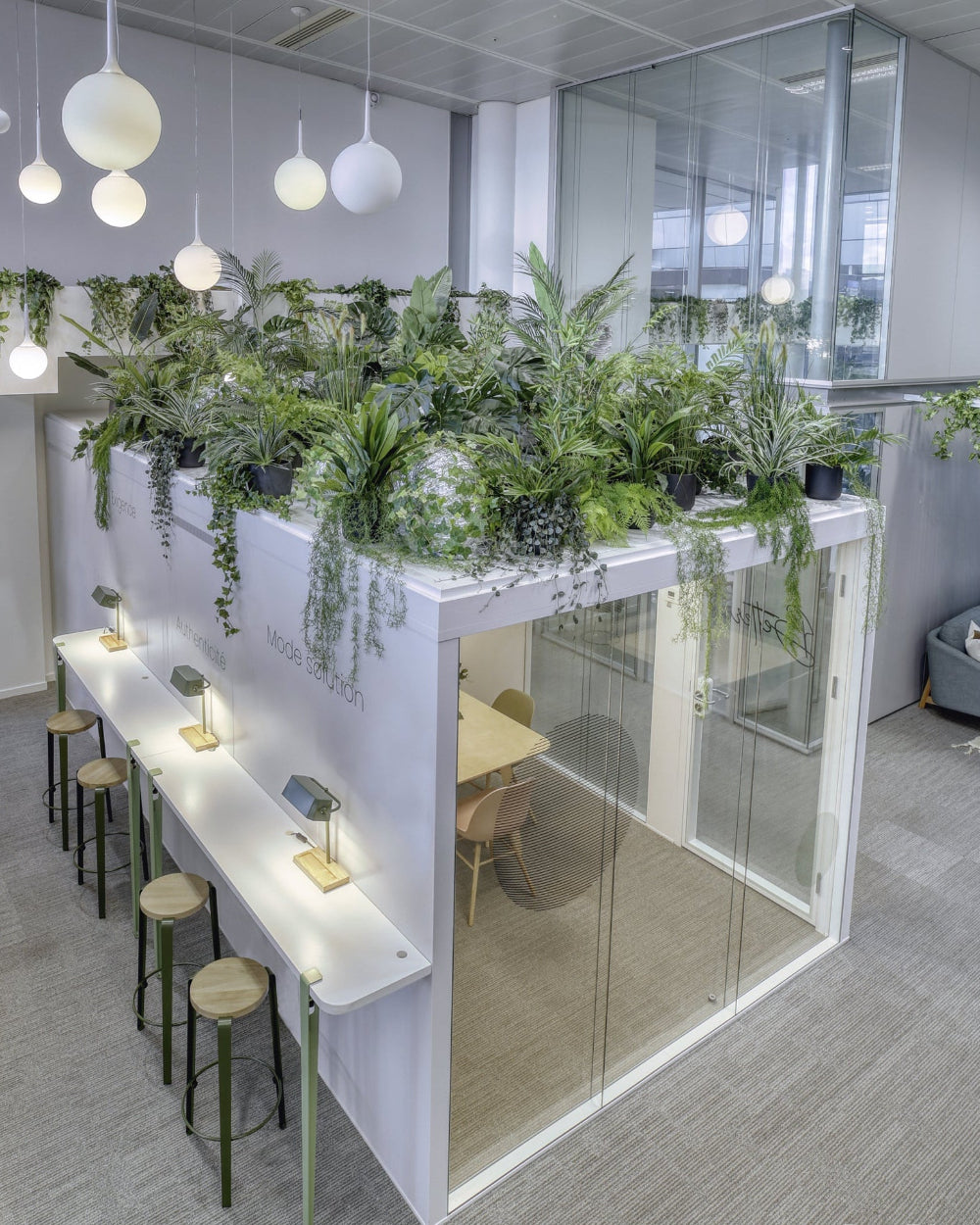 Modern office space at Payplug furnished with a raised garden wall filled with plants, stools, and tables from Enky. 