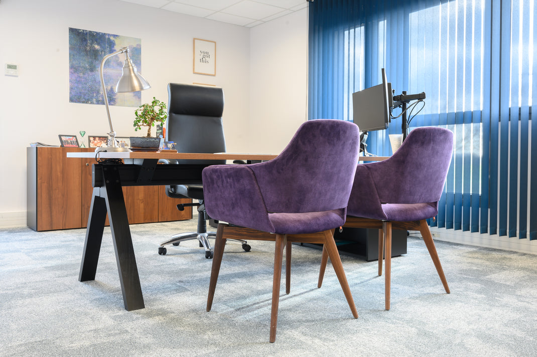 Modern office setup with purple chairs, desk, and computer monitors.