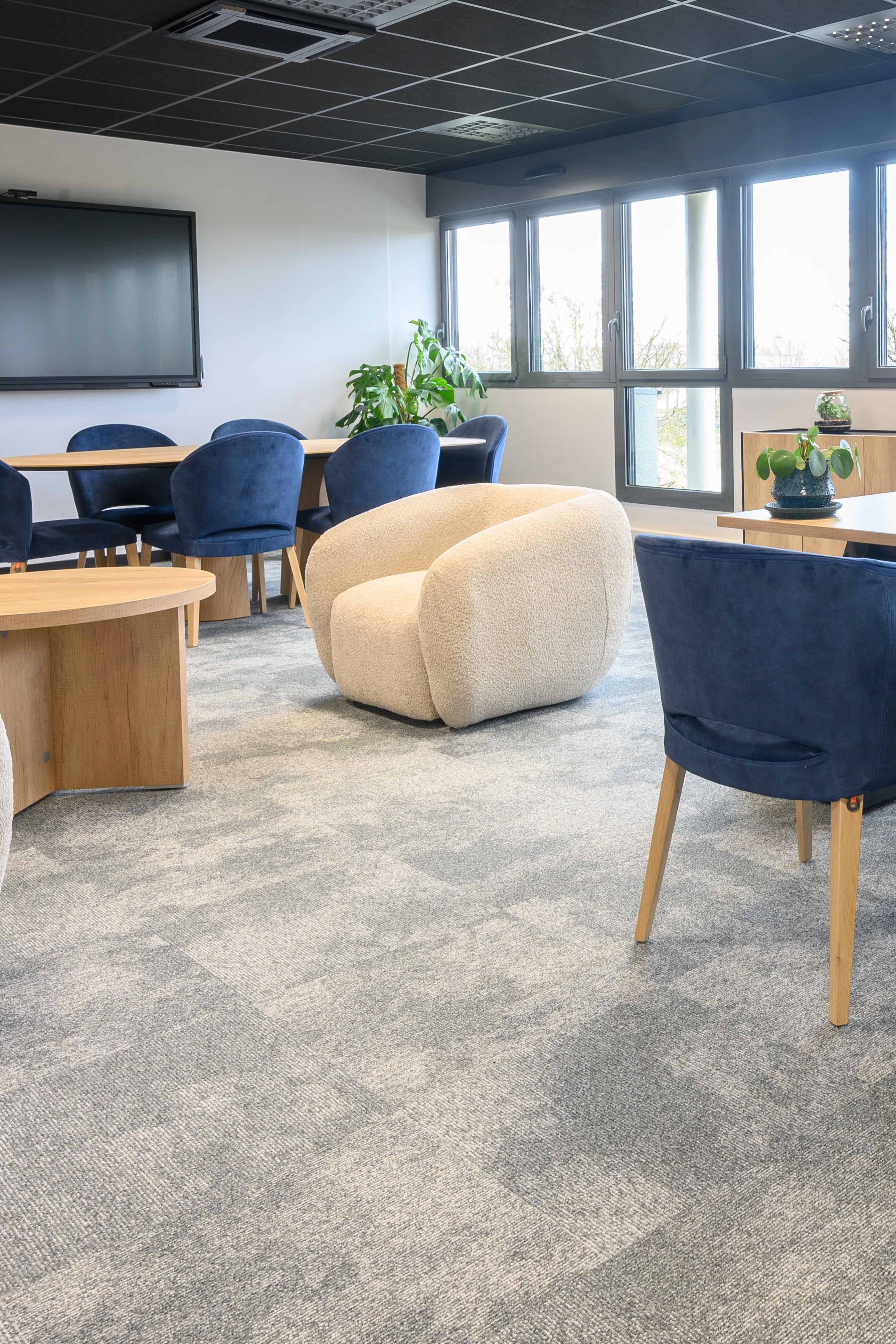 Modern office space with blue chairs, a large desk, and large windows.