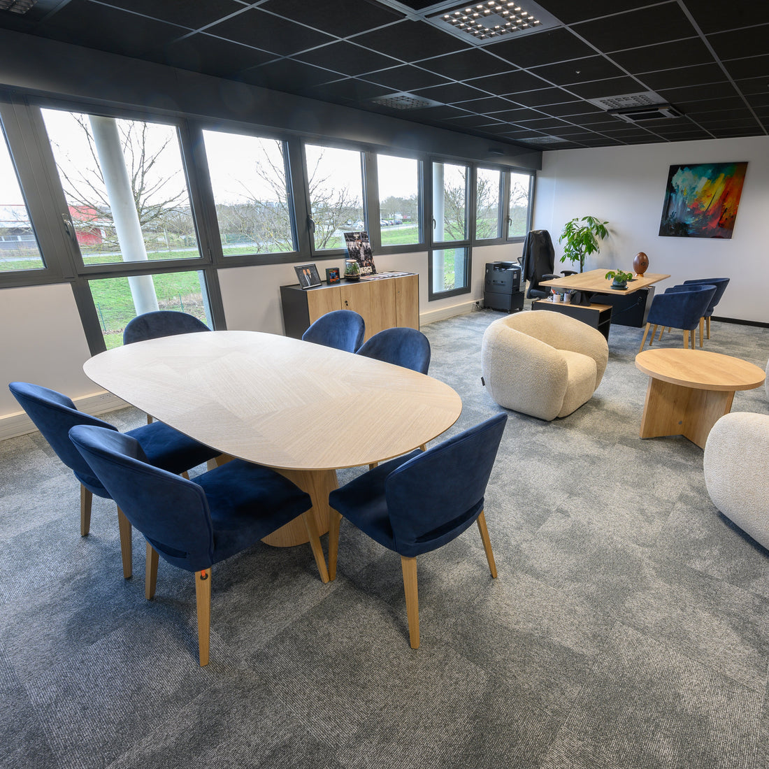 Modern office space with client welcoming desk and meeting round table and chairs in a well-lit room.