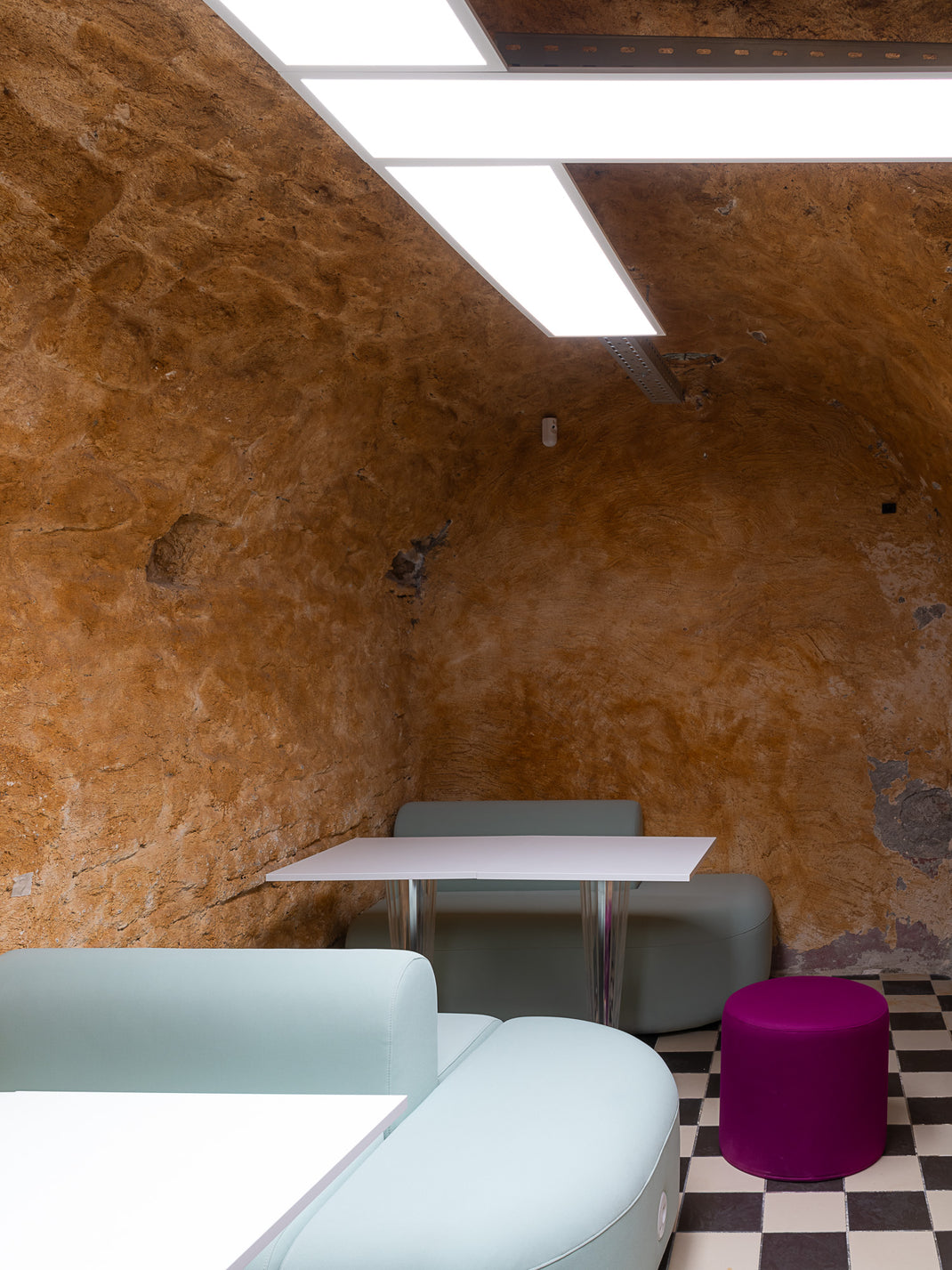 Modern interior with textured walls, a checkered floor, and minimal furniture.
