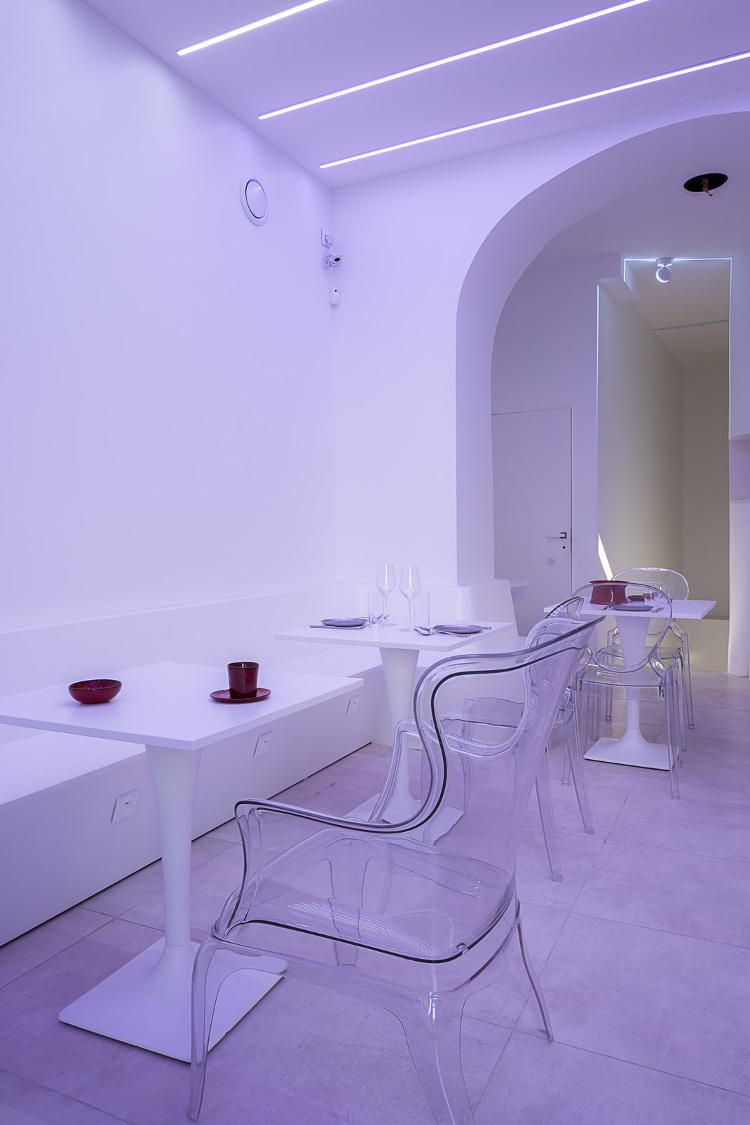 Modern dining area with white furniture and transparent chairs in a minimalistic setting.
