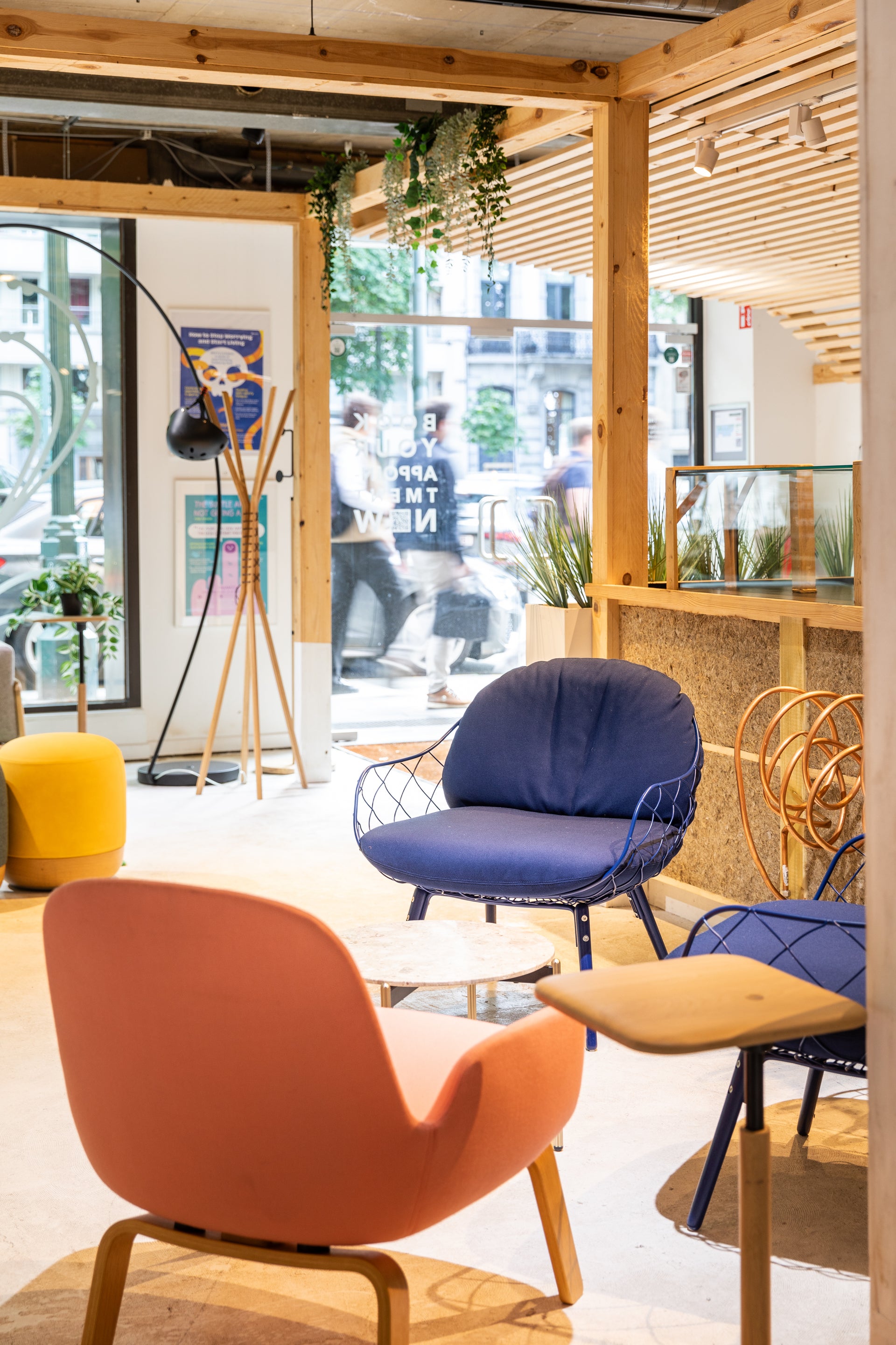 Modern interior with colorful chairs and a view of people outside through large windows.