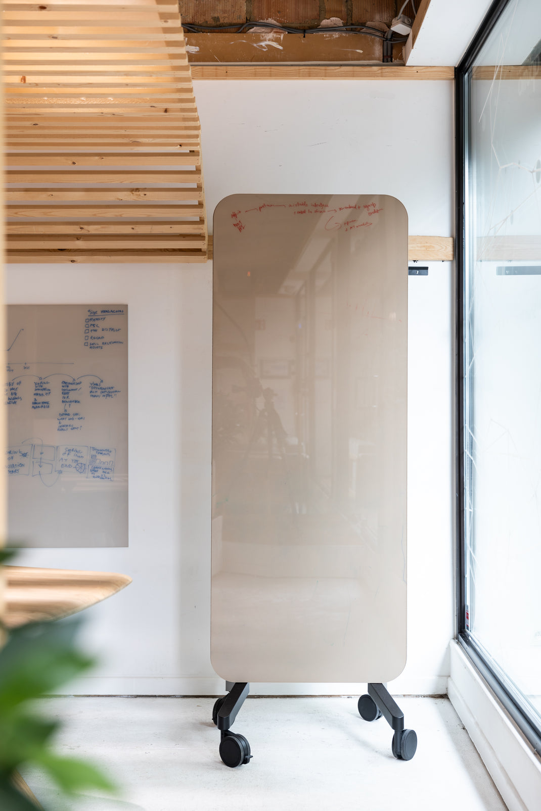 Rectangular whiteboard on wheels in a room with wooden accents and a large window.