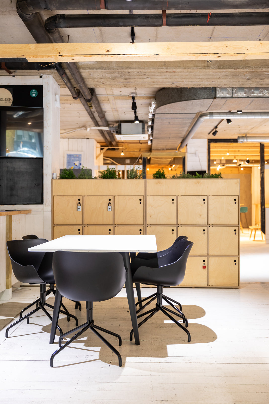 Meeting space with a table and chairs in front of wooden lockers.