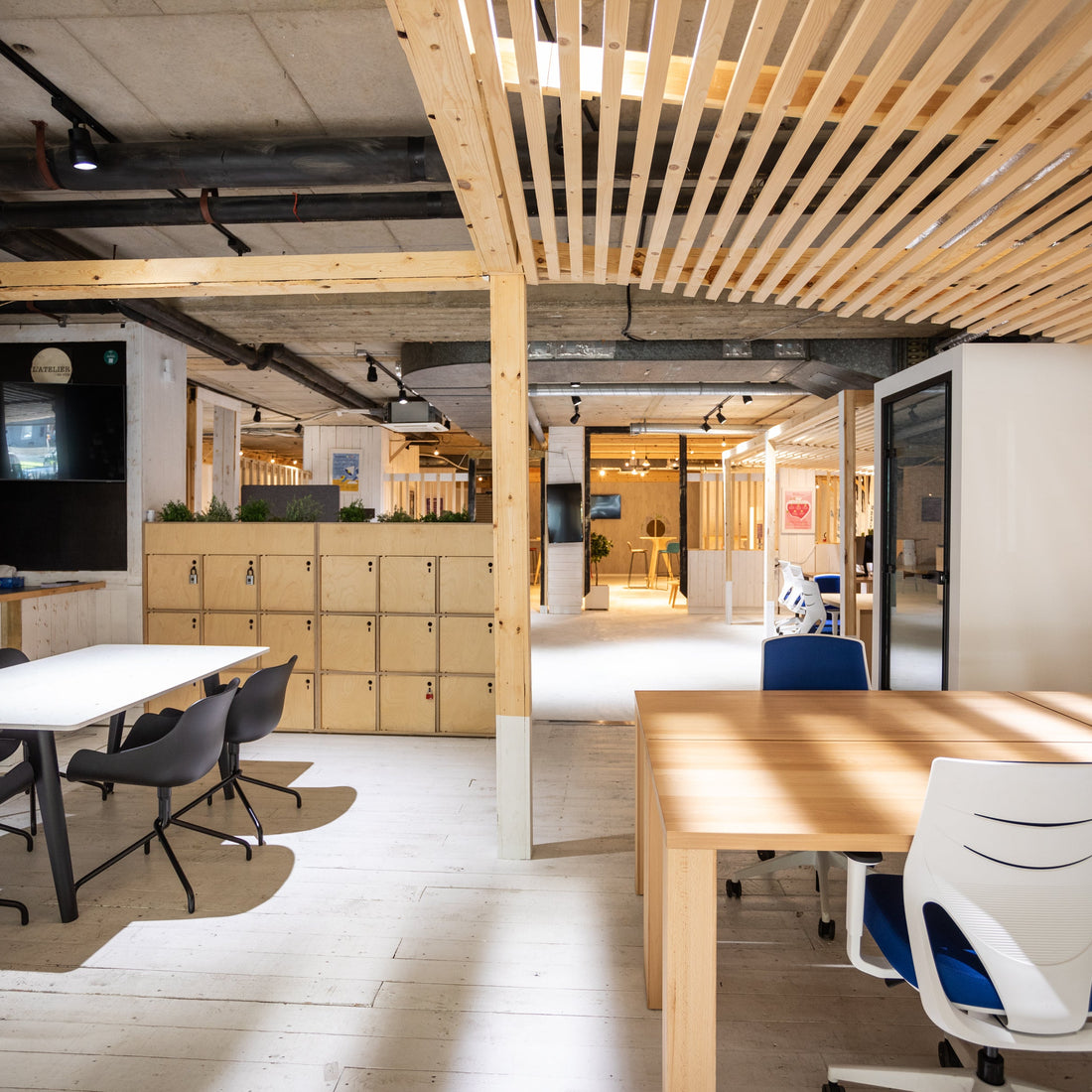 Modern office space with wooden tables, chairs, and a ceiling with exposed beams.
