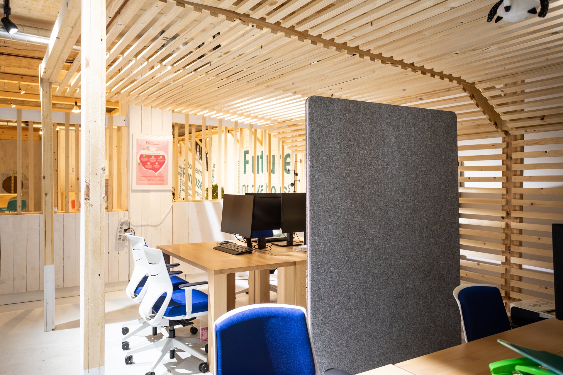 Modern office space with wooden walls, desks, and chairs.