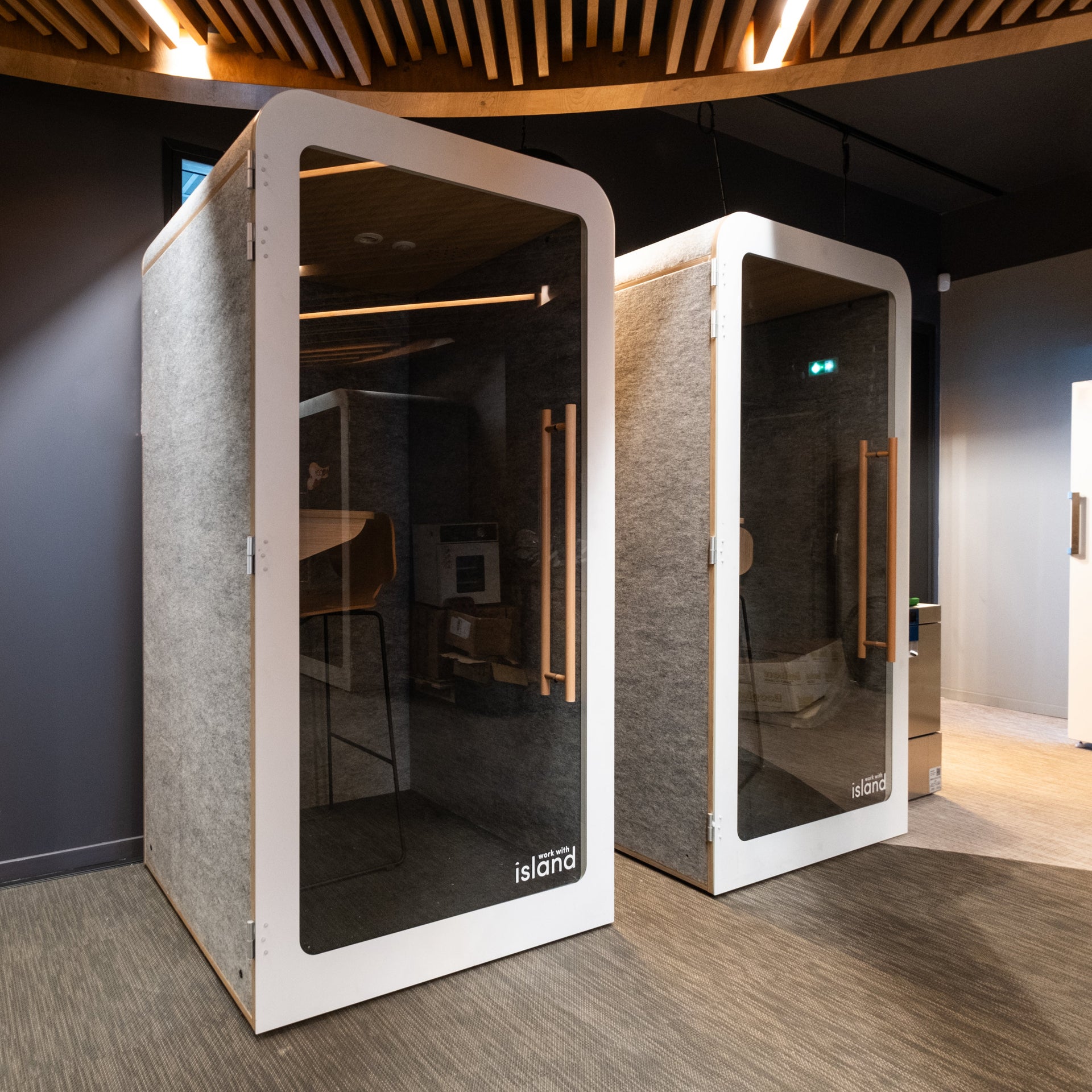 Two soundproofing booths in a room with a modern interior design.