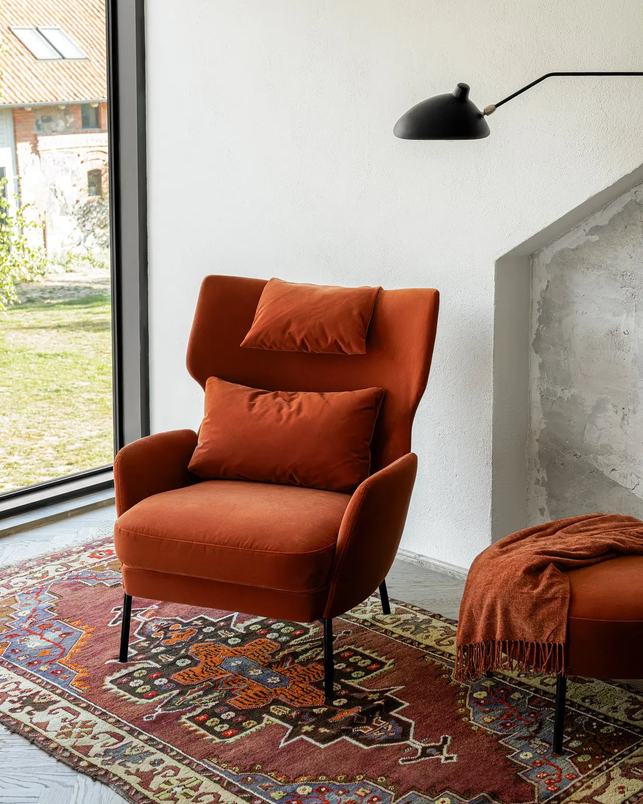 Orange armchair with cushions on a patterned rug in a modern living room.