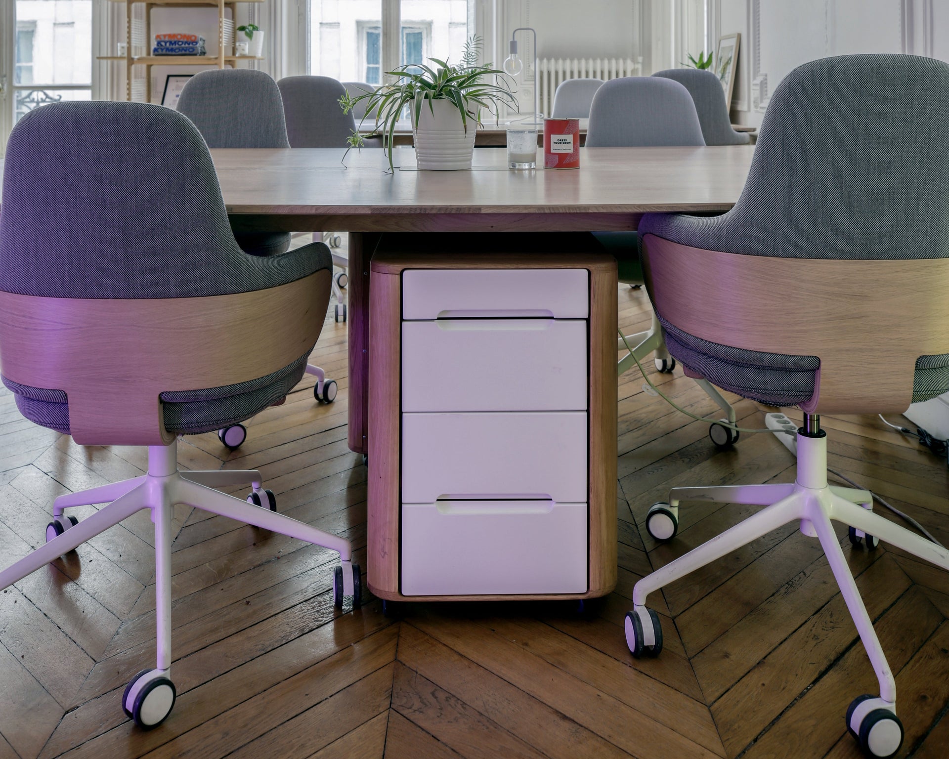 Modern office space with a long desk and chairs in a stylishly decorated room.