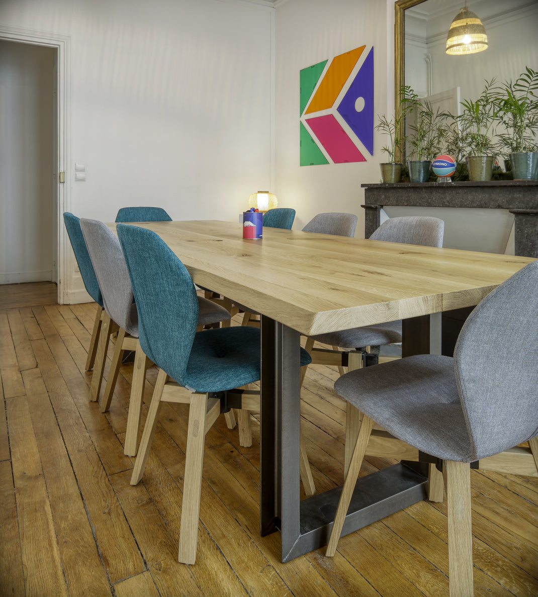 Dining area with wooden table and chairs in a room with a colorful abstract painting on the wall.