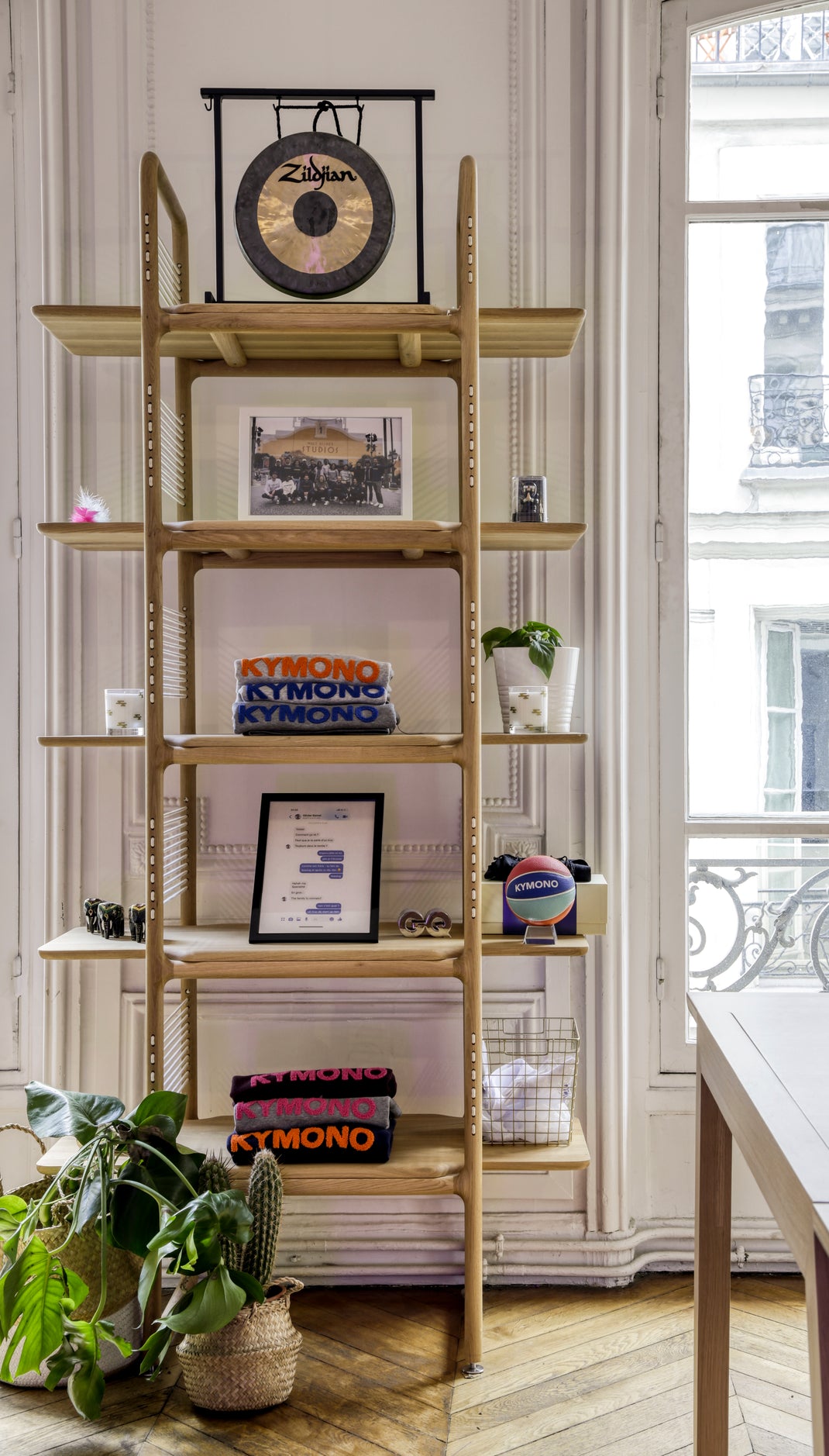 Wooden bookshelf with decorative items in a room with large windows.