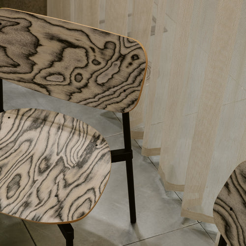 Three chairs with wood-patterned seats and backs in a room with tiled floor and striped wallpaper.