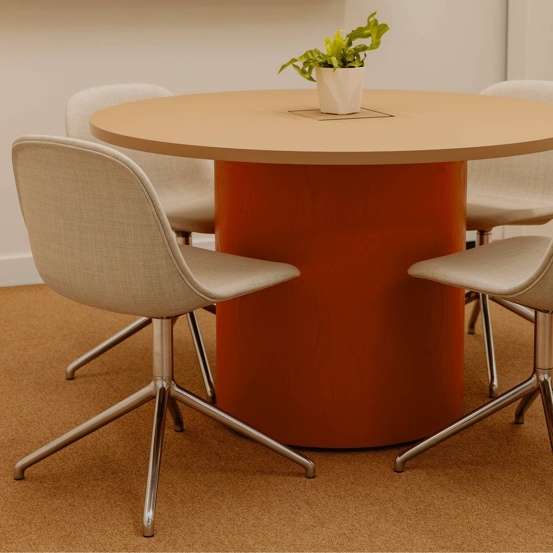Round wooden table with four beige chairs on a brown floor.