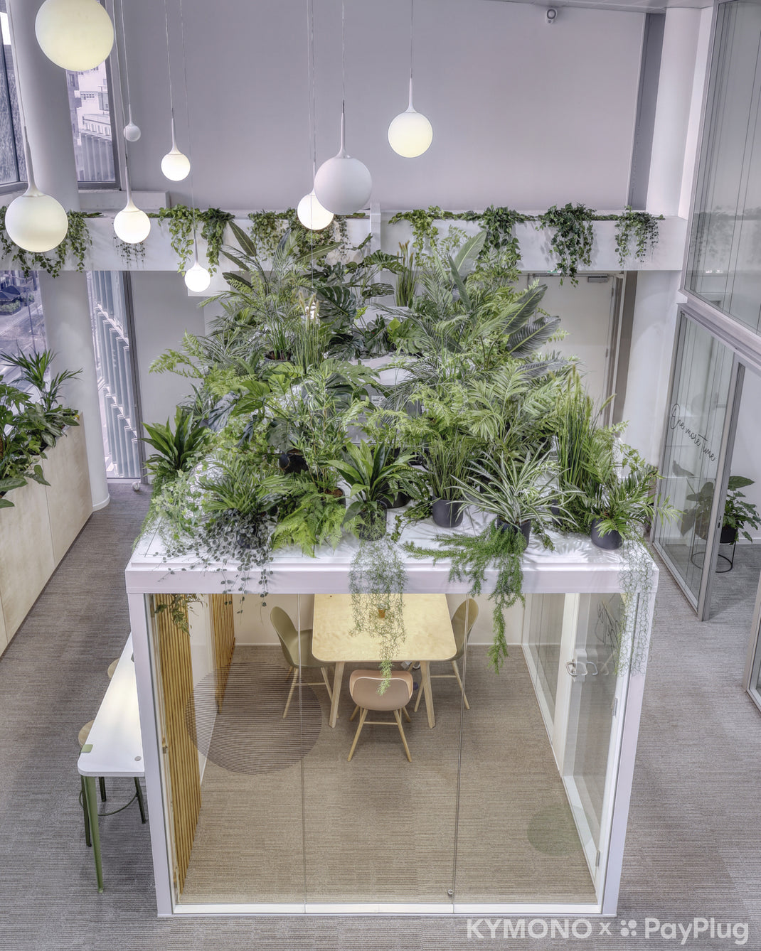 Modern modular office space with a large table and chairs, surrounded by green plants.