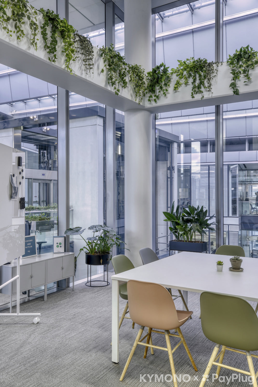 Modern office space with white tables, green chairs, and plants.