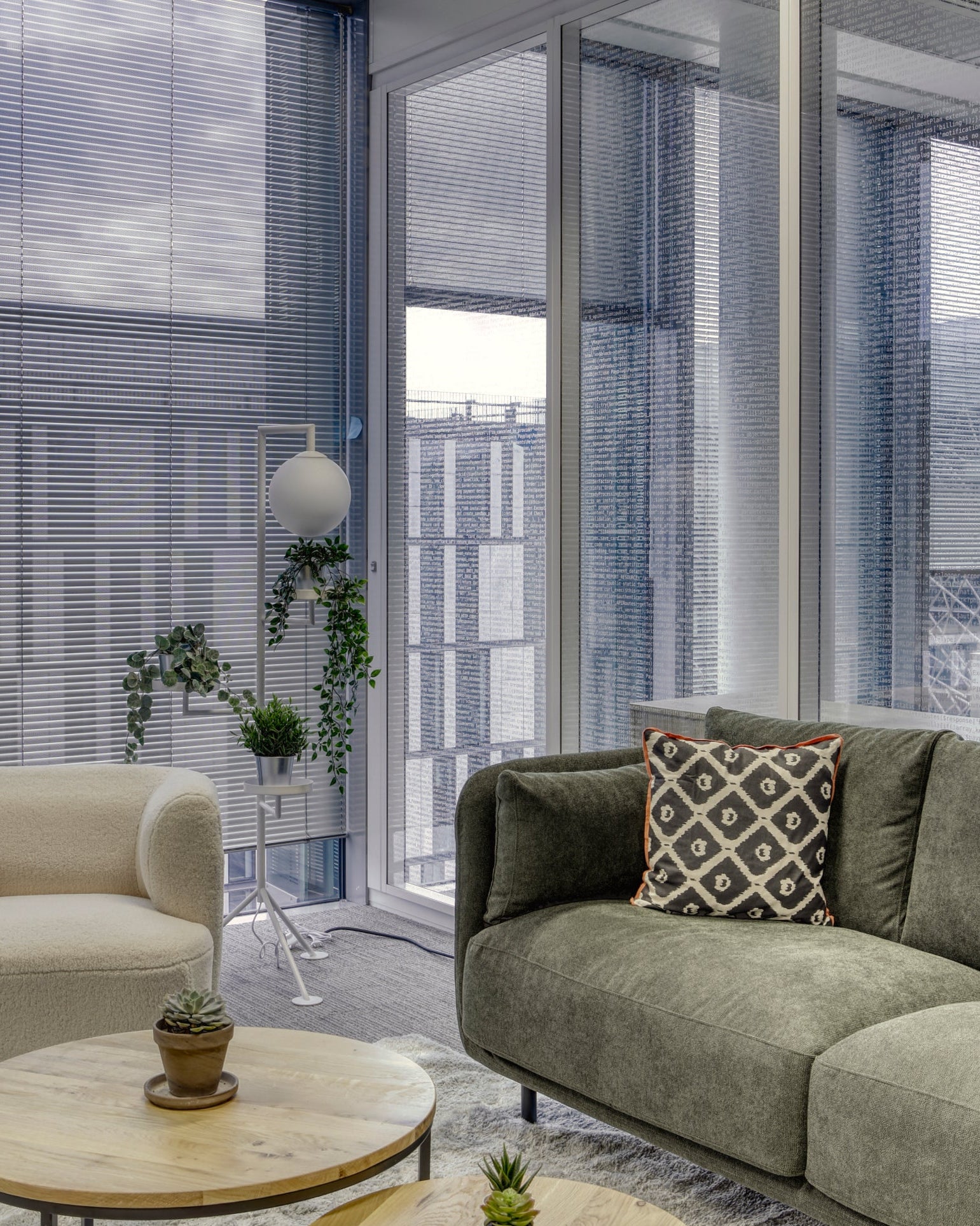 Modern living room with a green sofa, round wooden coffee table, and standing lamp in Payplug Office break out area. 