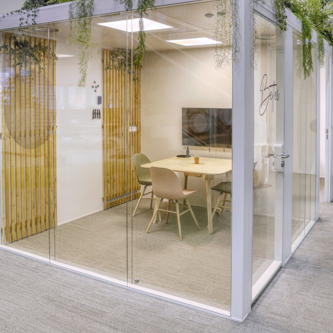 Modern modular office space with a glass partition, plants, and a desk.