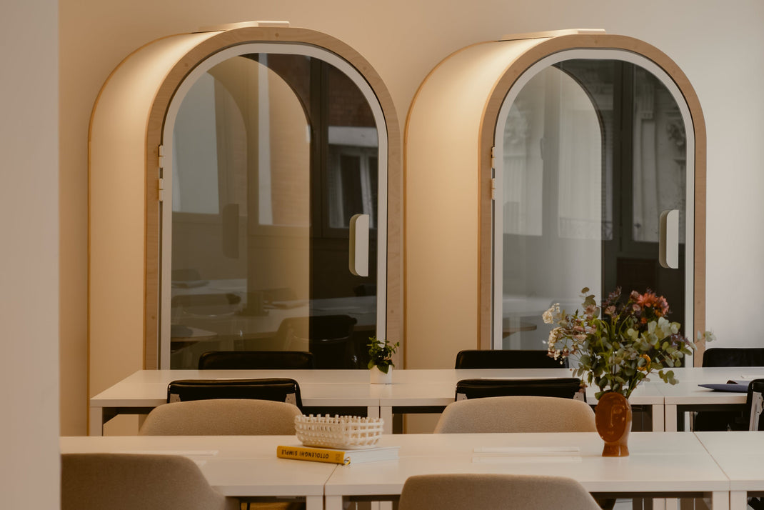 Two arched mirrors on a wall with a dining table and chairs in the foreground.