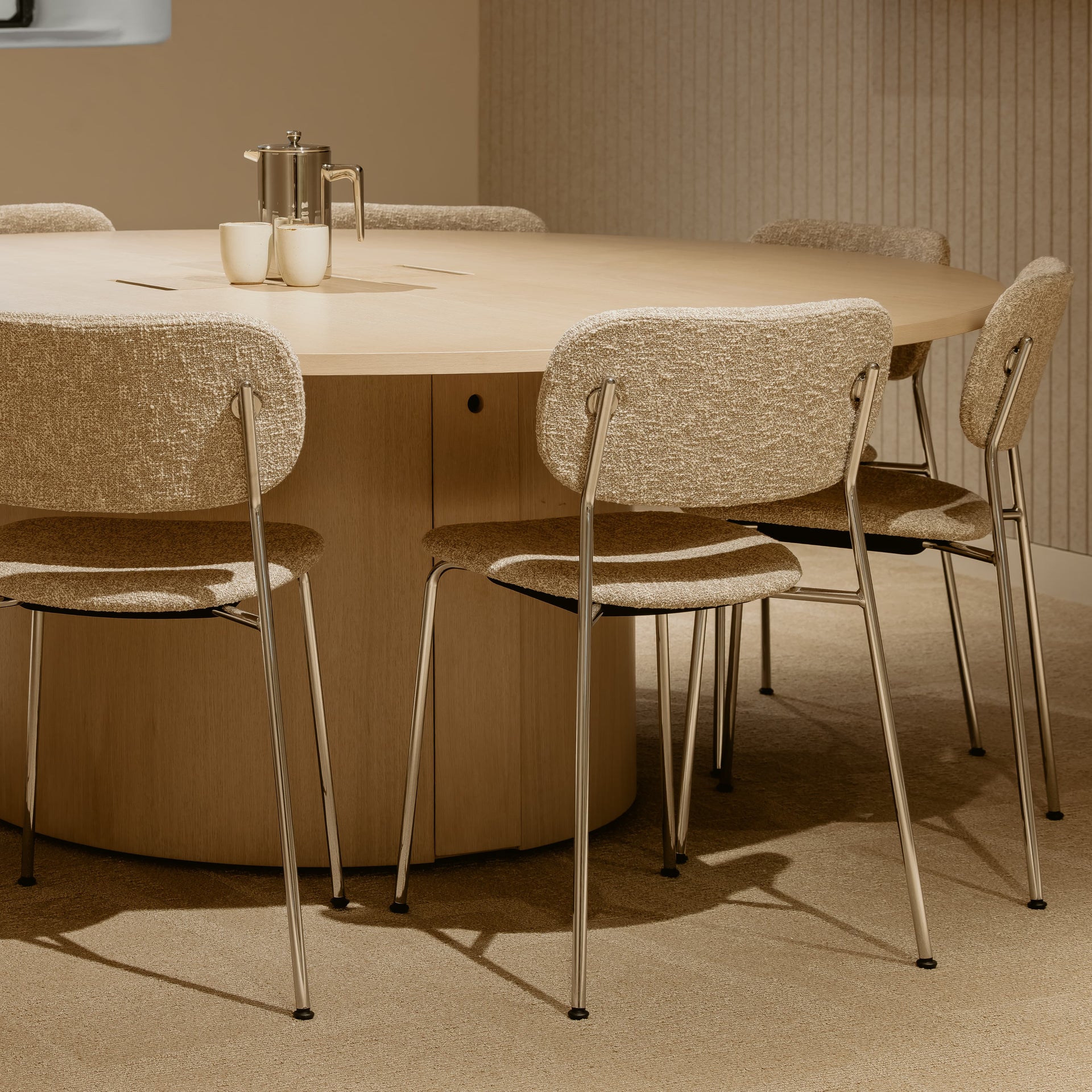 Round beige table with six matching chairs in a room with neutral walls.