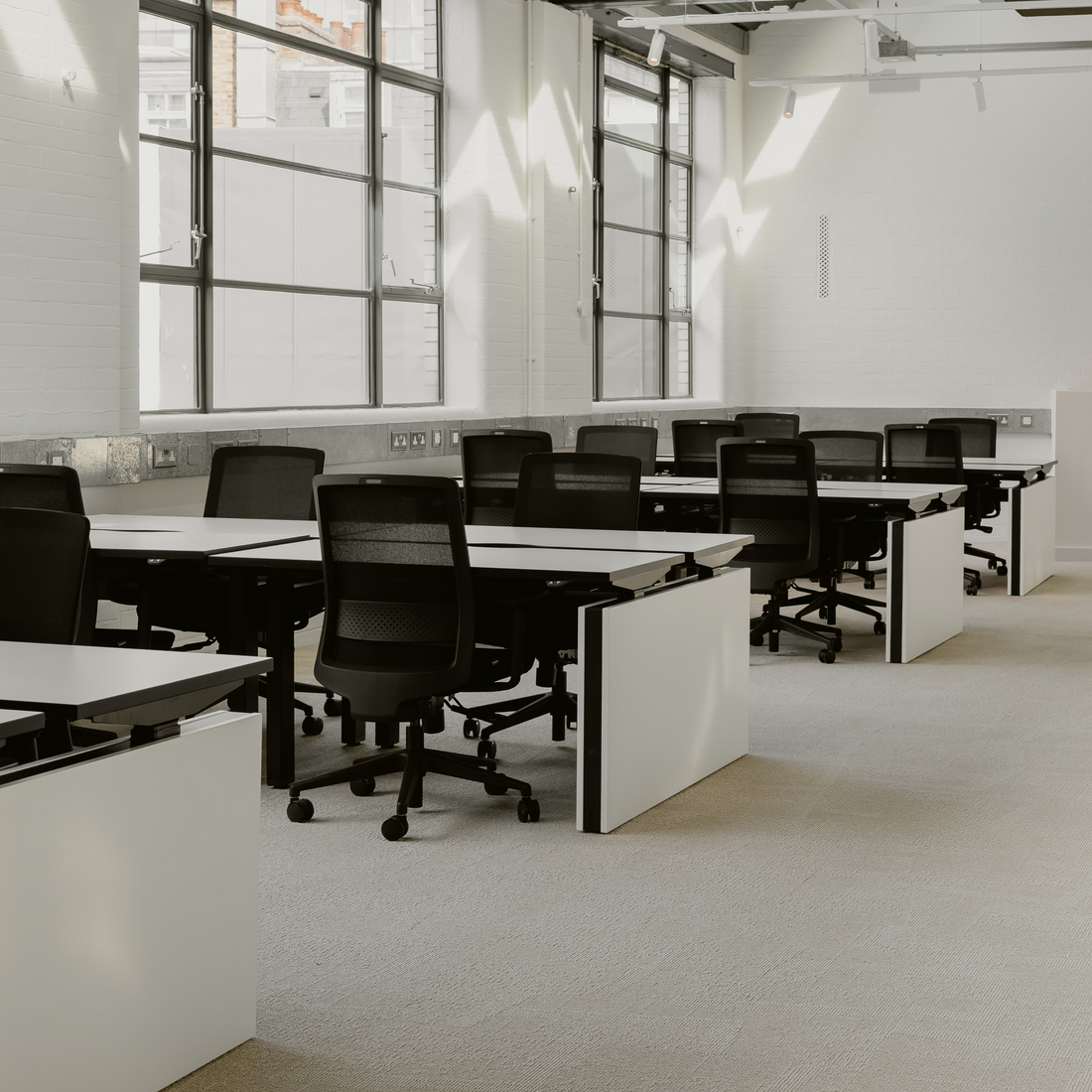 Modern office space with desks and chairs in a well-lit room.