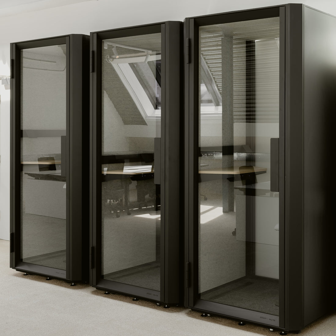 Black glass-enclosed office pods in a modern office setting