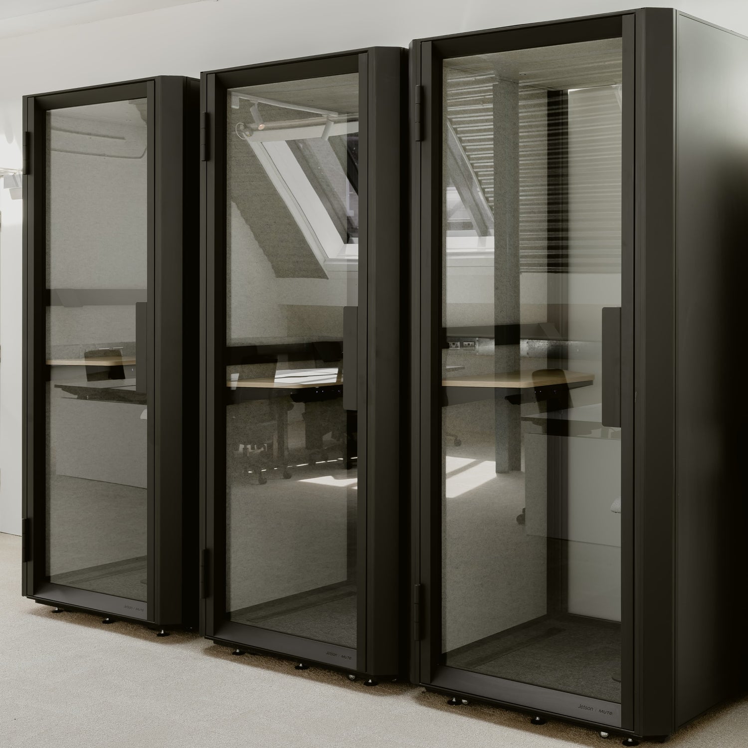 Black glass-enclosed office pods in a modern office setting