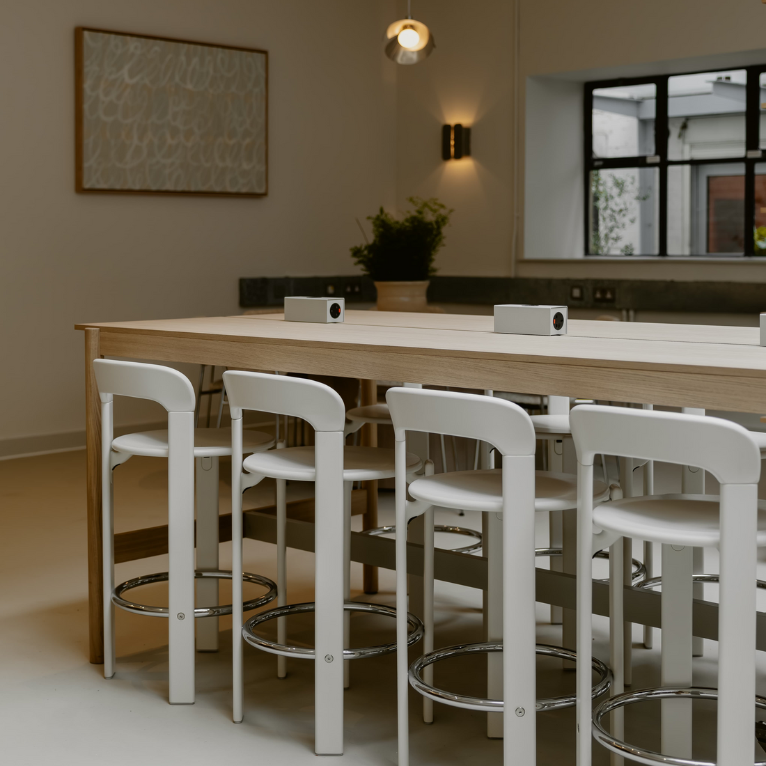 Modern kitchen with wooden dining table and white bar stools.