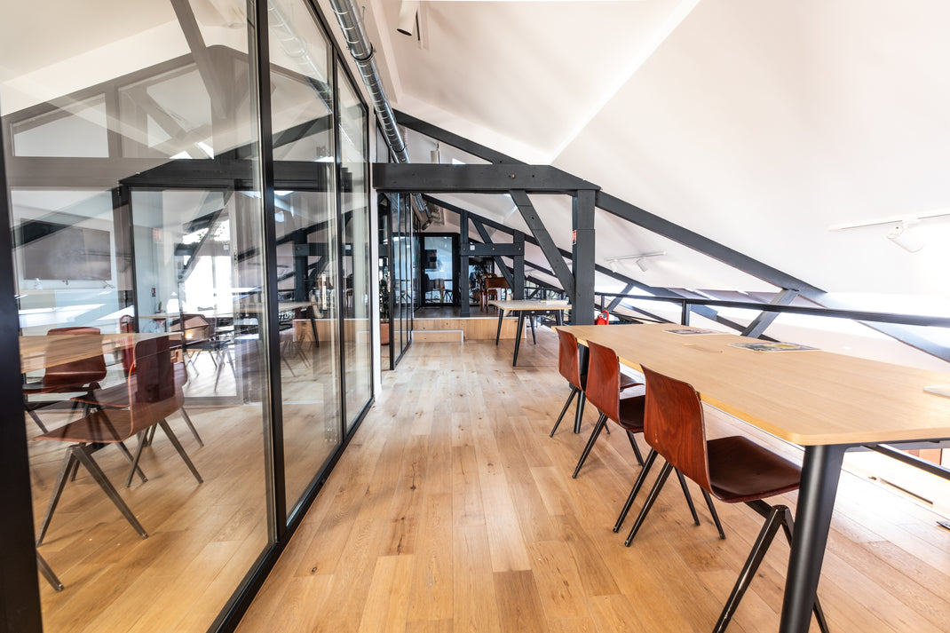 Modern office space with glass walls and wooden tables.