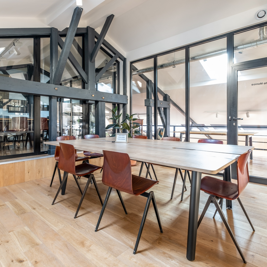 Modern office space with a long wooden table and red chairs.